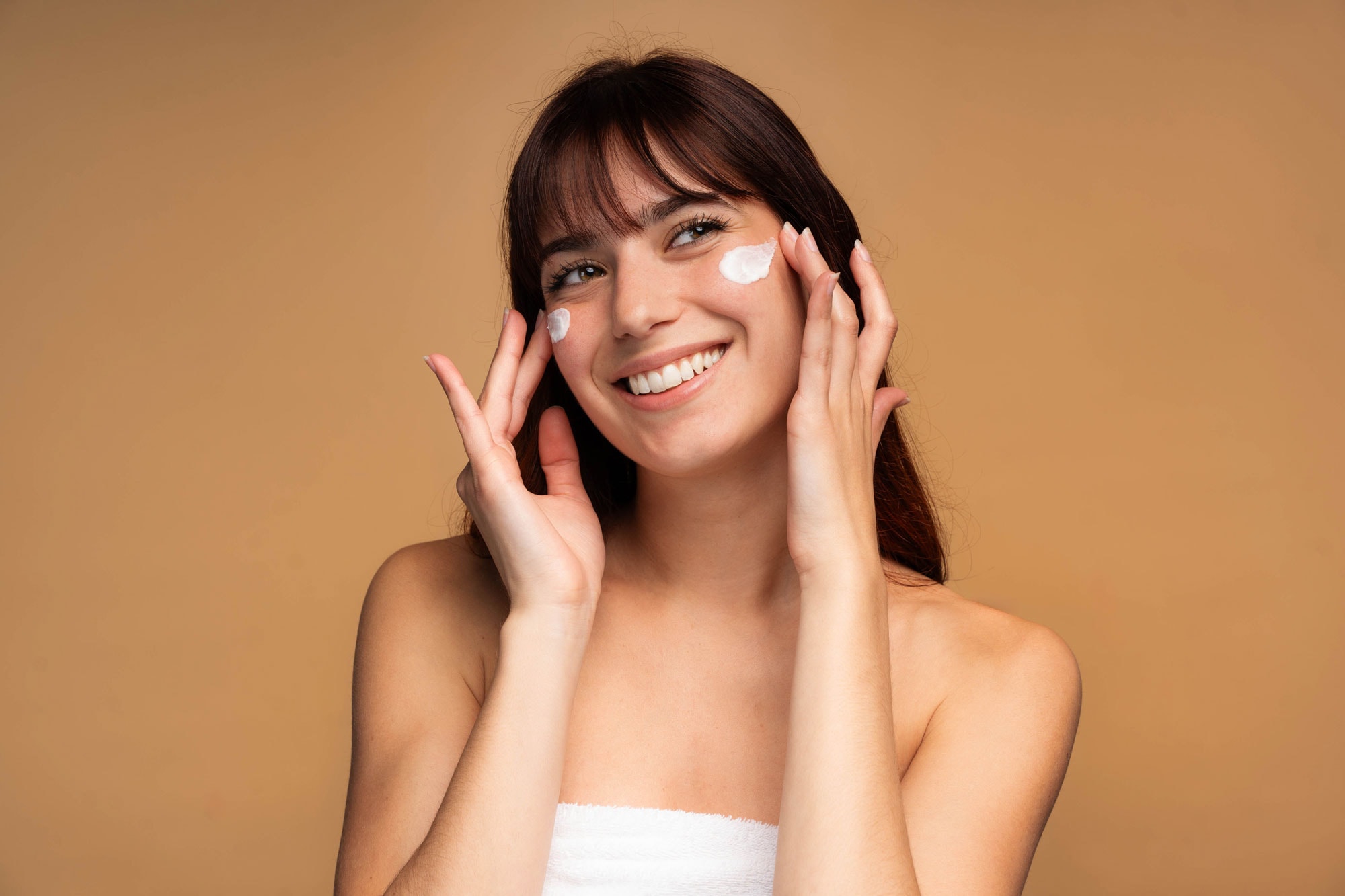 Woman applying facial cream representing differences between medical grade and over the counter skincare